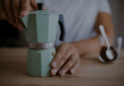 Hombre agarra elegantemente su cafetera italiana